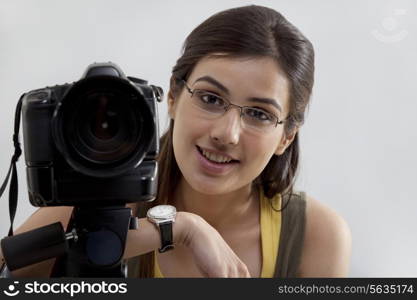 Portrait of a smiling young woman with digital camera