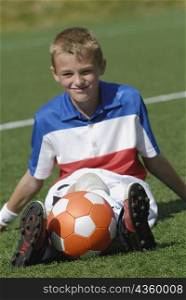 Portrait of a soccer player sitting with a soccer ball