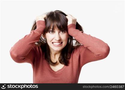 Portrait of a stressed young woman pulling her hair out, isolated over a gray background
