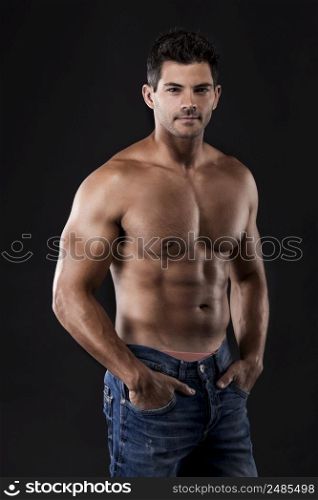 Portrait of a strong man posing without a shirt against dark background