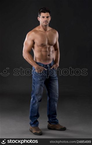 Portrait of a strong man posing without a shirt against dark background