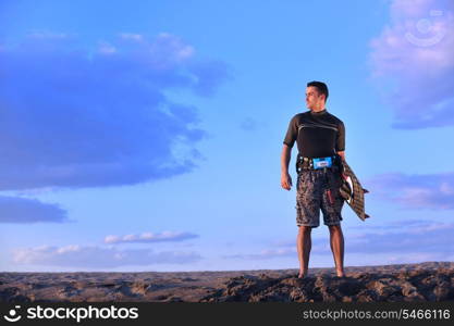 Portrait of a strong young surf man at beach on sunset in a contemplative mood with a surfboard