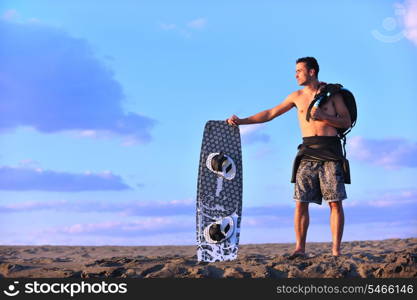 Portrait of a strong young surf man at beach on sunset in a contemplative mood with a surfboard