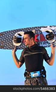 Portrait of a strong young surf man at beach on sunset in a contemplative mood with a surfboard