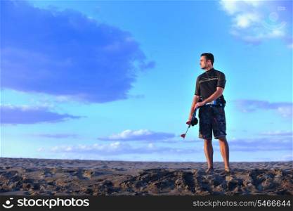 Portrait of a strong young surf man at beach on sunset in a contemplative mood with a surfboard