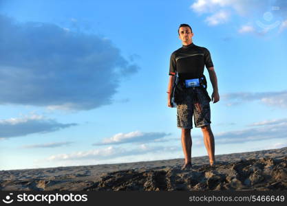 Portrait of a strong young surf man at beach on sunset in a contemplative mood with a surfboard