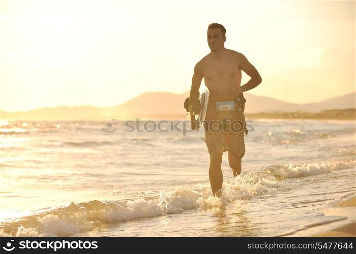 Portrait of a strong young surf man at beach on sunset in a contemplative mood with a surfboard