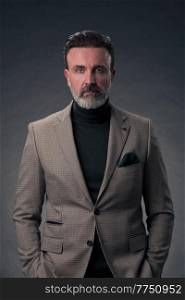 Portrait of a stylish elegant senior businessman with a beard and casual business clothes in photo studio isolated on dark background gesturing with hands. High quality photo. Portrait of a stylish elegant senior businessman with a beard and casual business clothes in photo studio isolated on dark background gesturing with hands