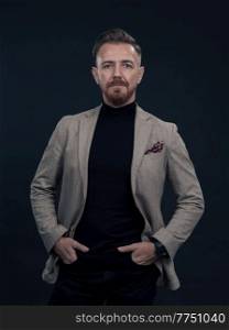Portrait of a successful stylish elegant senior businessman with a grey beard and casual business clothes confident in photo studio isolated on dark background gesturing with hands. High-quality photo. Portrait of a stylish elegant senior businessman with a beard and casual business clothes in photo studio isolated on dark background gesturing with hands