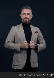 Portrait of a successful stylish elegant senior businessman with a grey beard and casual business clothes confident in photo studio isolated on dark background gesturing with hands. High-quality photo. Portrait of a stylish elegant senior businessman with a beard and casual business clothes in photo studio isolated on dark background gesturing with hands