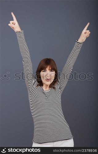 Portrait of a successful young woman with arm up over a grey background