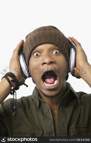 Portrait of a surprised young African American man listening music through headphones