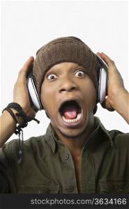 Portrait of a surprised young African American man listening music through headphones