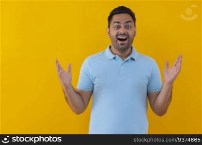 Portrait of a surprised young man looking at camera against yellow background