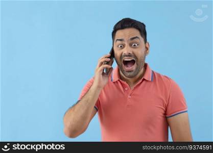 Portrait of a surprised young man talking on Smartphone