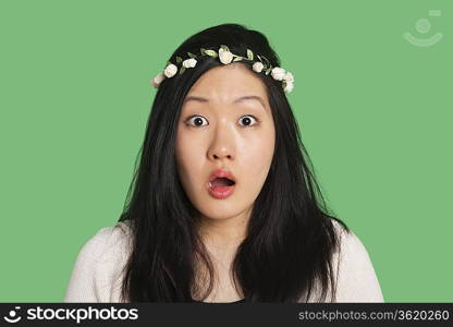 Portrait of a surprised young woman over green background