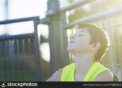 Portrait of a teen relaxing and dreaming on a basketball court with sunlight effect