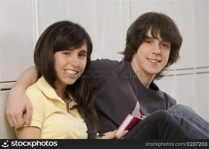 Portrait of a teenage boy arm around with a teenage girl and smiling