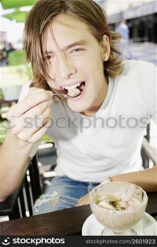 Portrait of a teenage boy eating an ice-cream sundae