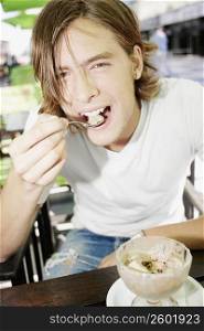 Portrait of a teenage boy eating an ice-cream sundae