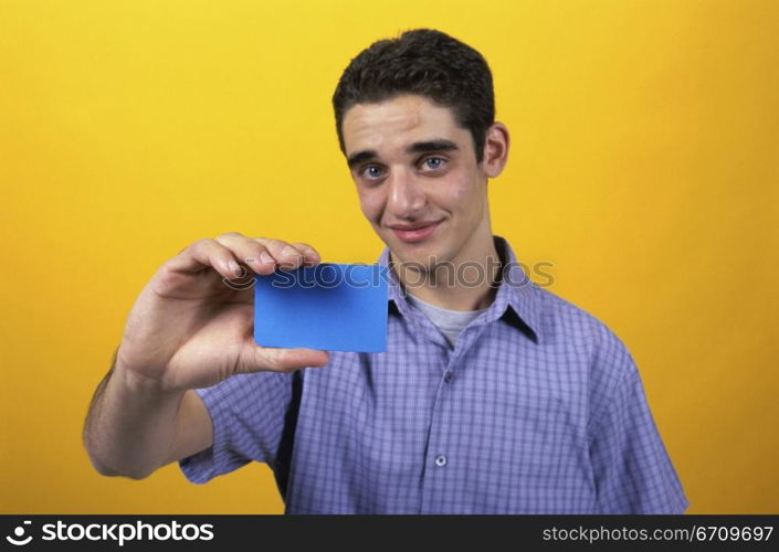 Portrait of a teenage boy holding a card