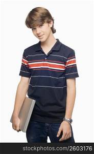 Portrait of a teenage boy holding a laptop