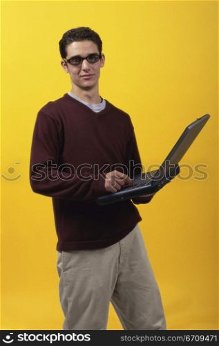 Portrait of a teenage boy holding a laptop