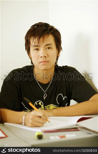 Portrait of a teenage boy holding a pen on a notepad