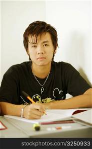 Portrait of a teenage boy holding a pen on a notepad