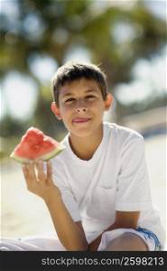 Portrait of a teenage boy holding a slice of watermelon