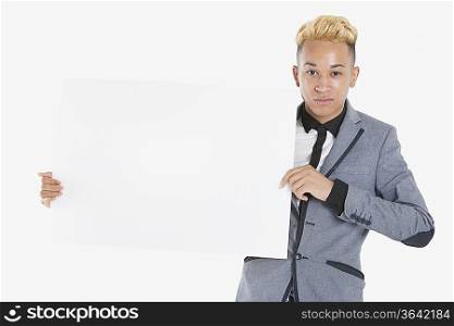 Portrait of a teenage boy holding blank cardboard over gray background