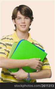 Portrait of a teenage boy holding books and ring binders