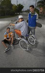 Portrait of a teenage boy on a low rider bicycle with his two friends beside him