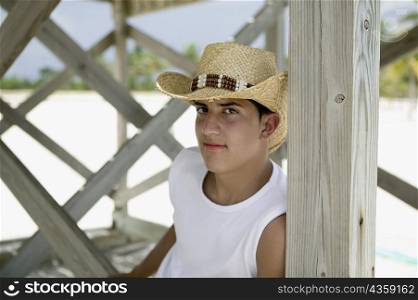 Portrait of a teenage boy sitting and wearing a straw hat