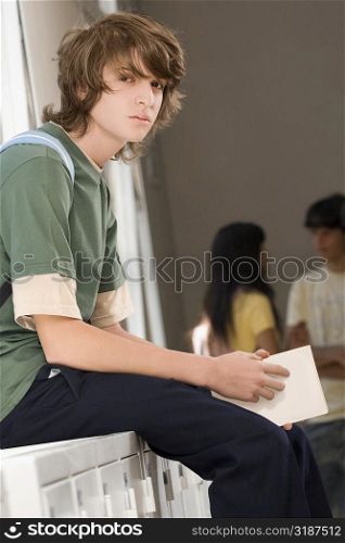 Portrait of a teenage boy sitting on a cabinet and looking serious