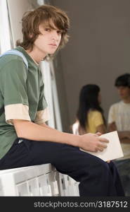 Portrait of a teenage boy sitting on a cabinet and looking serious