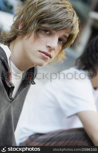 Portrait of a teenage boy sitting with his friend behind him