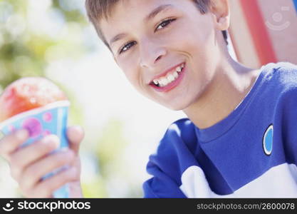 Portrait of a teenage boy smiling and holding an ice-cream cone