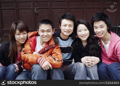 Portrait of a teenage boy smiling with two young men and two young women