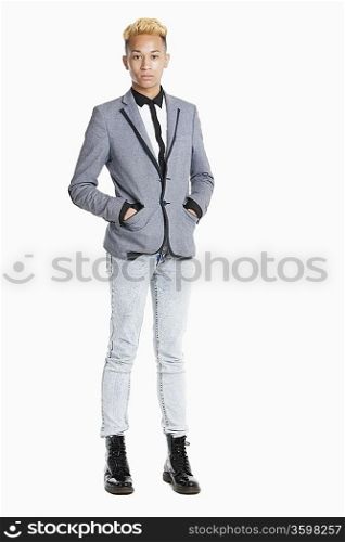 Portrait of a teenage boy standing in smart casuals over gray background
