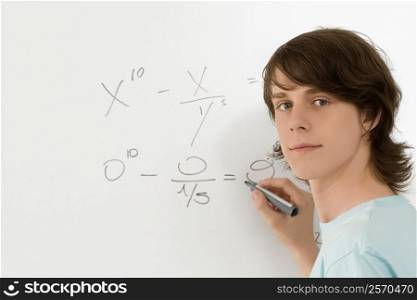 Portrait of a teenage boy writing on a whiteboard