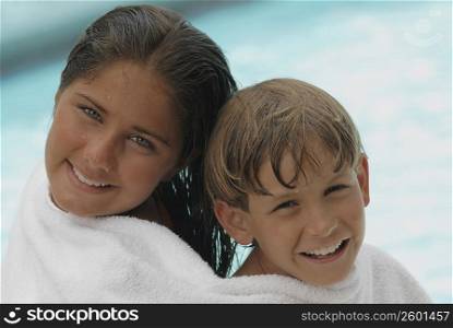 Portrait of a teenage girl and her brother wrapped in a towel and smiling
