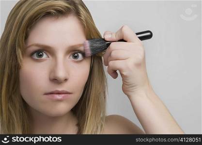 Portrait of a teenage girl applying blush on her face