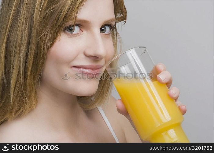 Portrait of a teenage girl drinking a glass of orange juice