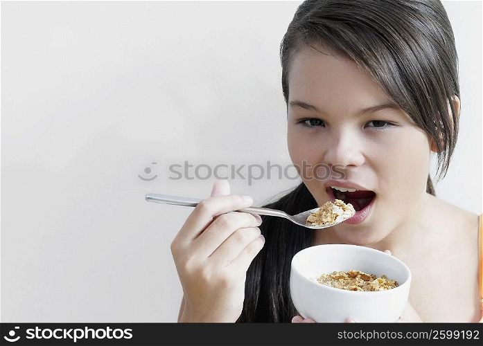 Portrait of a teenage girl eating a bowl of corn flakes