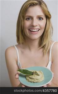 Portrait of a teenage girl holding a bowl of face pack and smiling