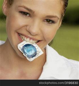 Portrait of a teenage girl holding a condom in her mouth