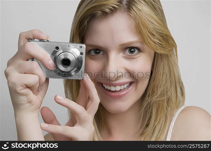 Portrait of a teenage girl holding a digital camera and smiling