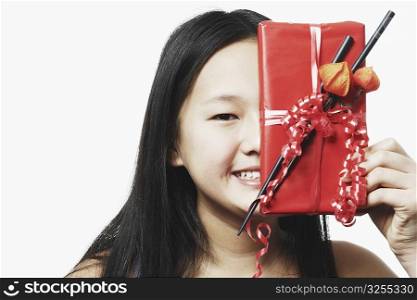 Portrait of a teenage girl holding a gift in front of her face