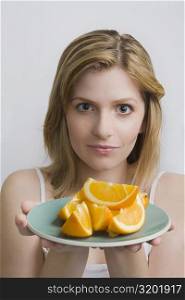 Portrait of a teenage girl holding a plate of oranges